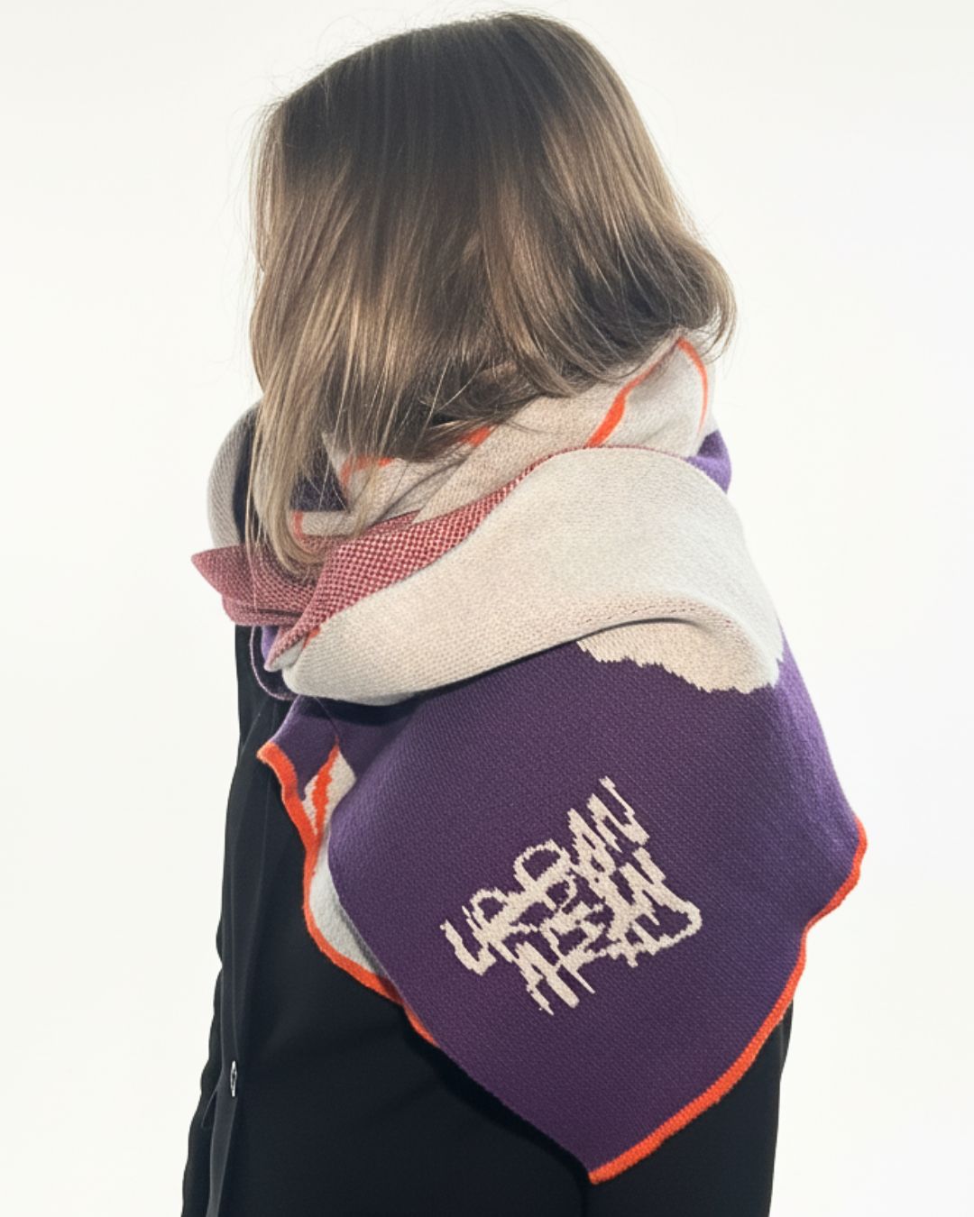 Person wearing a colorful scarf with 'Urban Outfitters' branding on a white background
