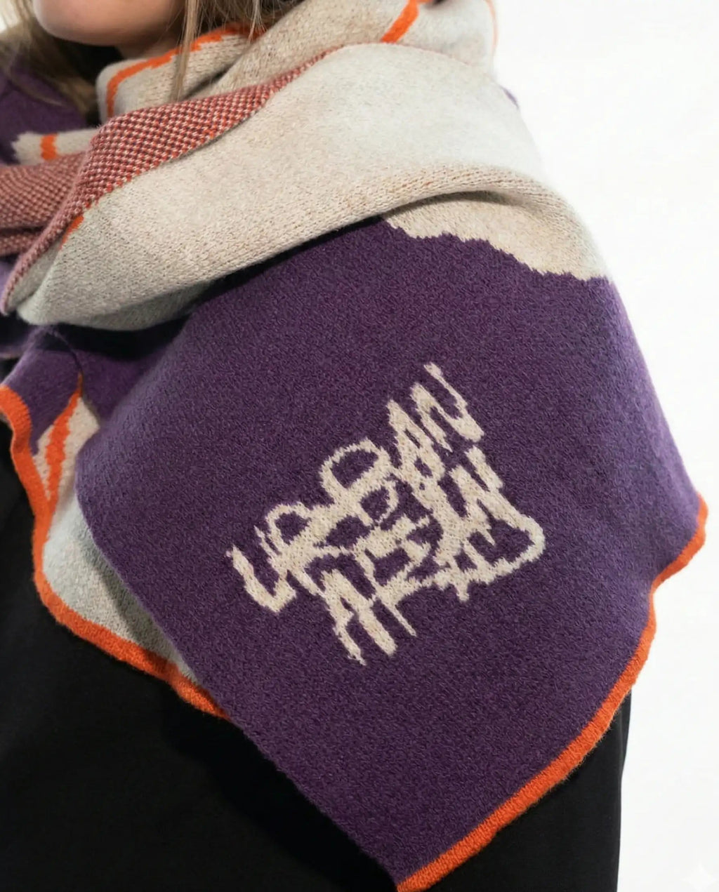 Close up of a scarf of Fine Merino Wool. with Urban Aran Logo in a violet background